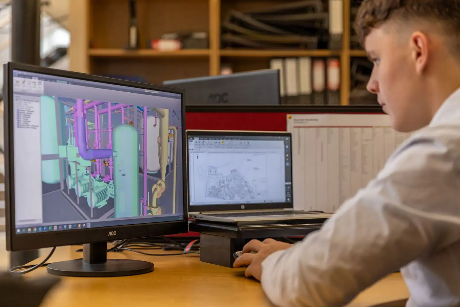 Personne devant une station de travail multi-écrans, un modèle 3D affiché sur le moniteur principal