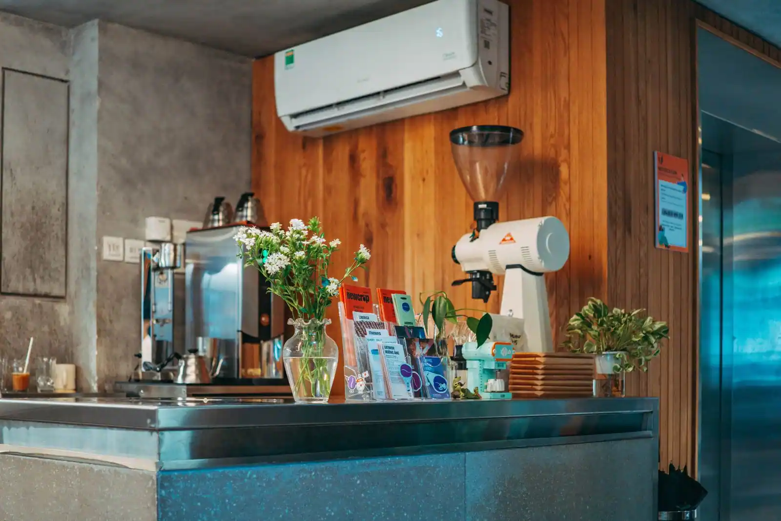 Comptoir d'un café équipé d'une machine à expresso et d'un moulin à grains, avec un petit bouquet.