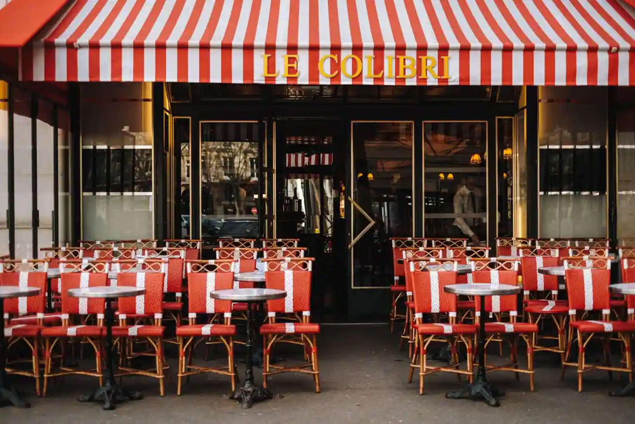 Terrasse d'une brasserie de style parisien, chaises en rotin et tables rondes installées sur le trottoir
