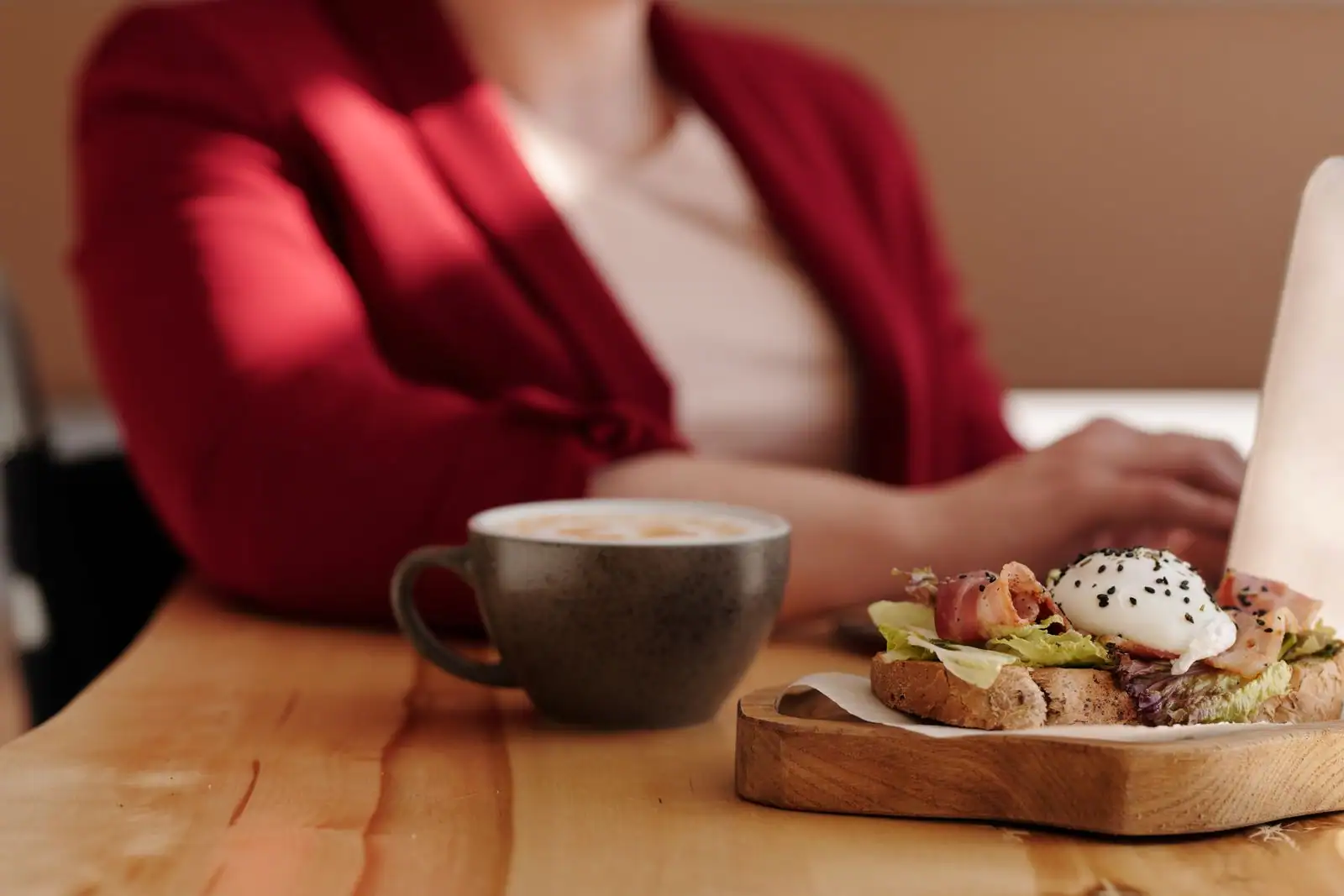 Tartine garnie d'un œuf poché et tasse de café sur une table en bois, dans un café