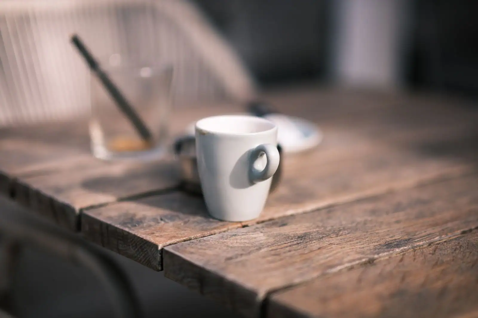 Tasse à café blanche posée sur une table en bois patinée dans un café