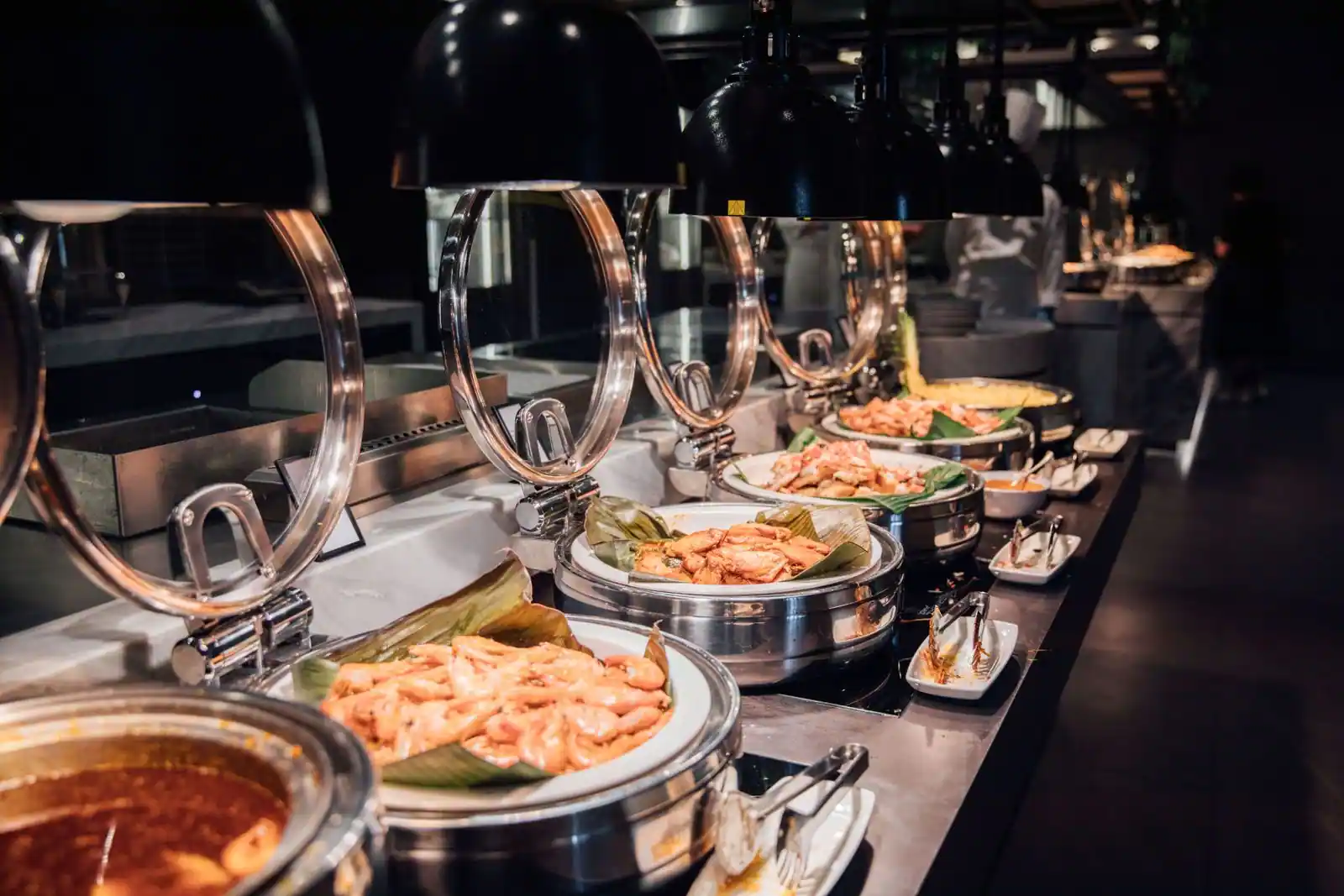 Comptoir d'un buffet asiatique garni de plats de fruits de mer sous des lampes chauffantes