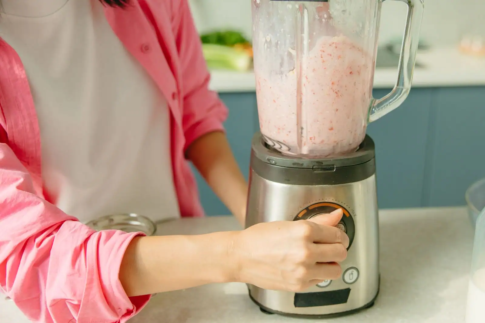 Main réglant la commande d'un blender de cuisine pendant la préparation d'un smoothie