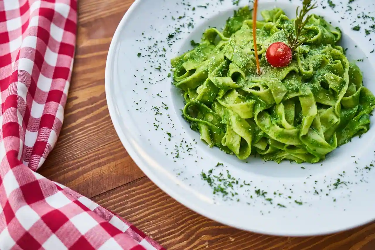 Assiette de pâtes en rubans nappées de pesto de basilic, garnie d'une tomate cerise