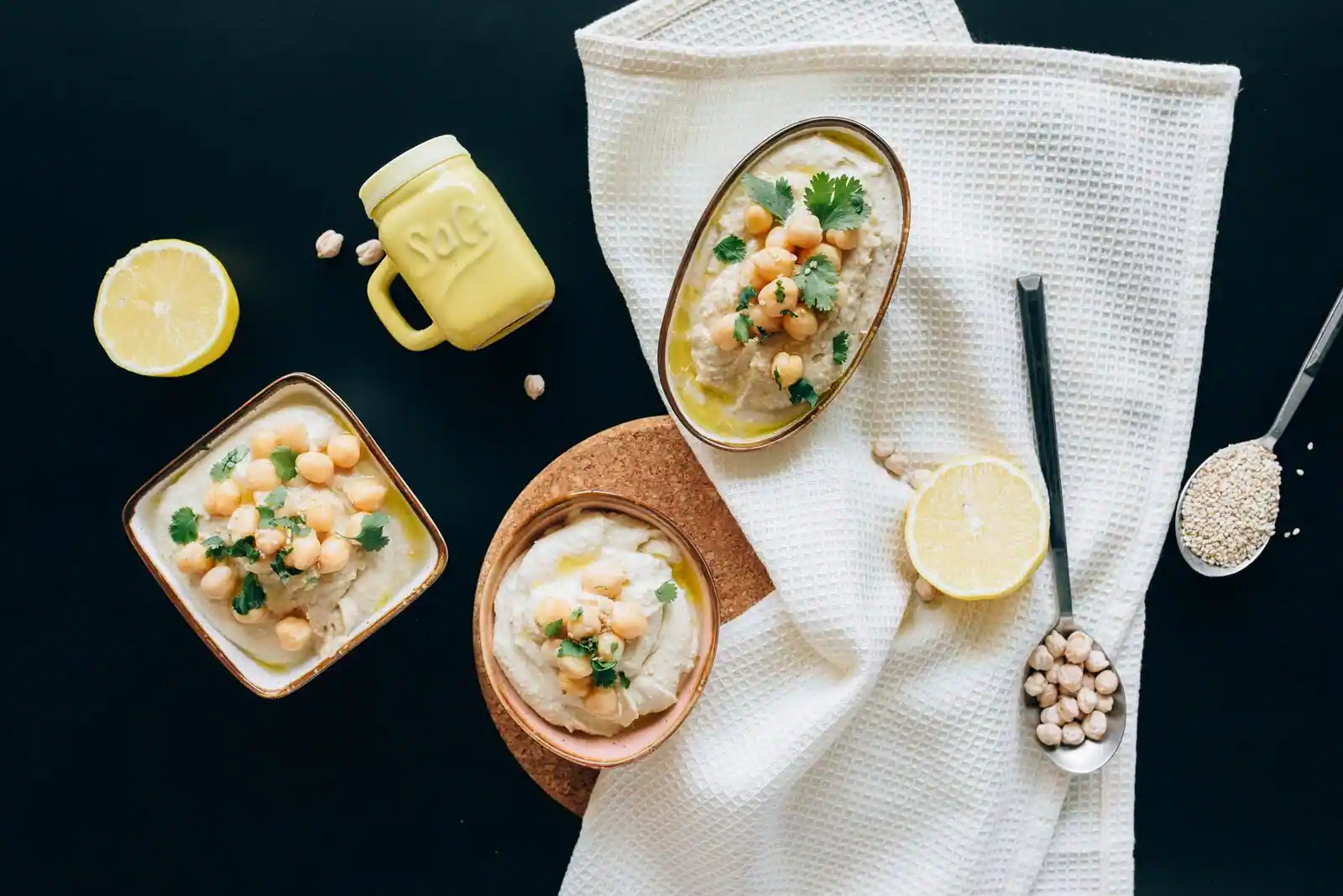 Bols de houmous garnis de pois chiches, coriandre et huile d'olive, avec citron et sésame