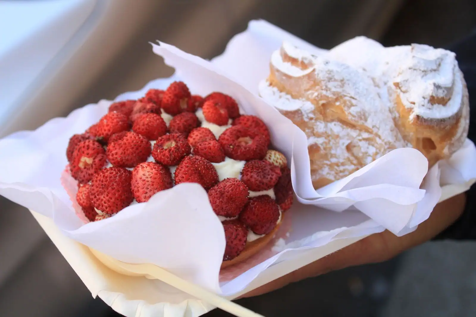 Tartelette aux fraises fraîches garnie de crème, accompagnée d'un chou saupoudré de sucre glace.