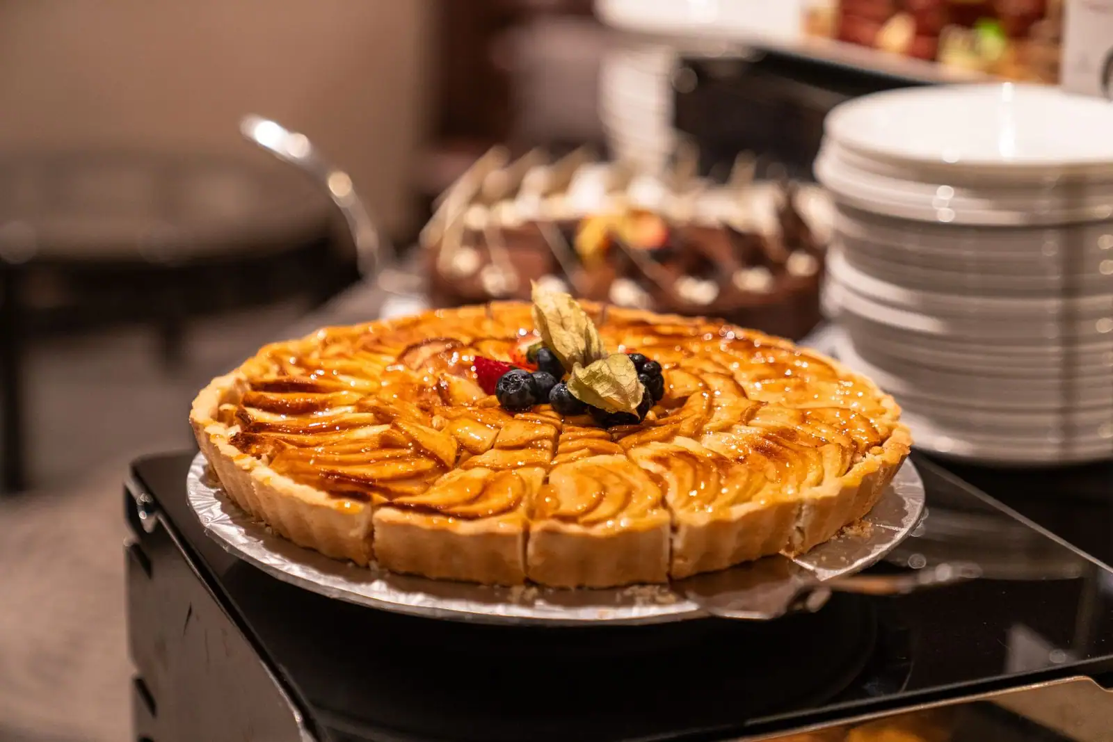 Tarte aux pommes dorée aux lamelles disposées en rosace, présentée sur un plat rond