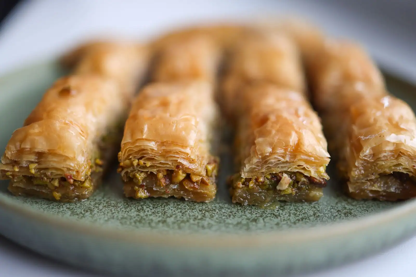 Baklavas roulés à la pistache, fine pâte feuilletée dorée et sirop, sur une assiette