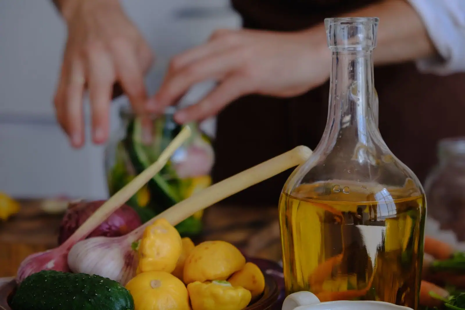 Bouteille d'huile d'olive entourée de légumes frais lors d'une préparation de cuisine méditerranéenne