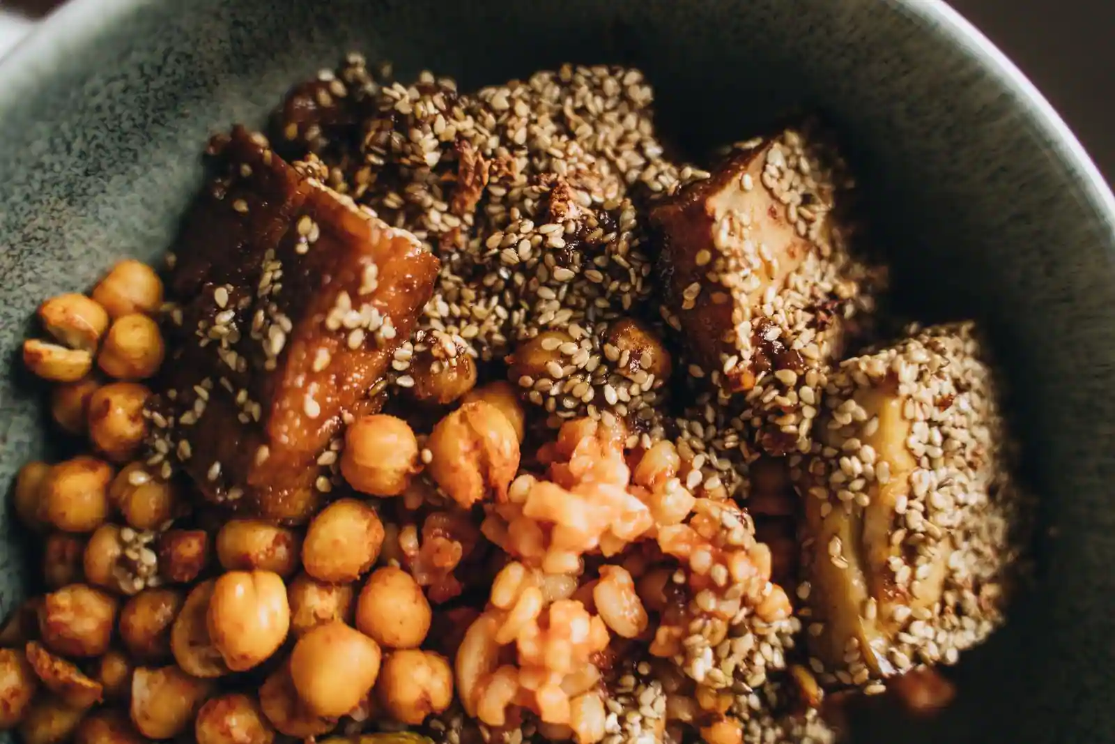 Bol vegan composé de pois chiches rôtis et de morceaux de tofu enrobés de graines de sésame
