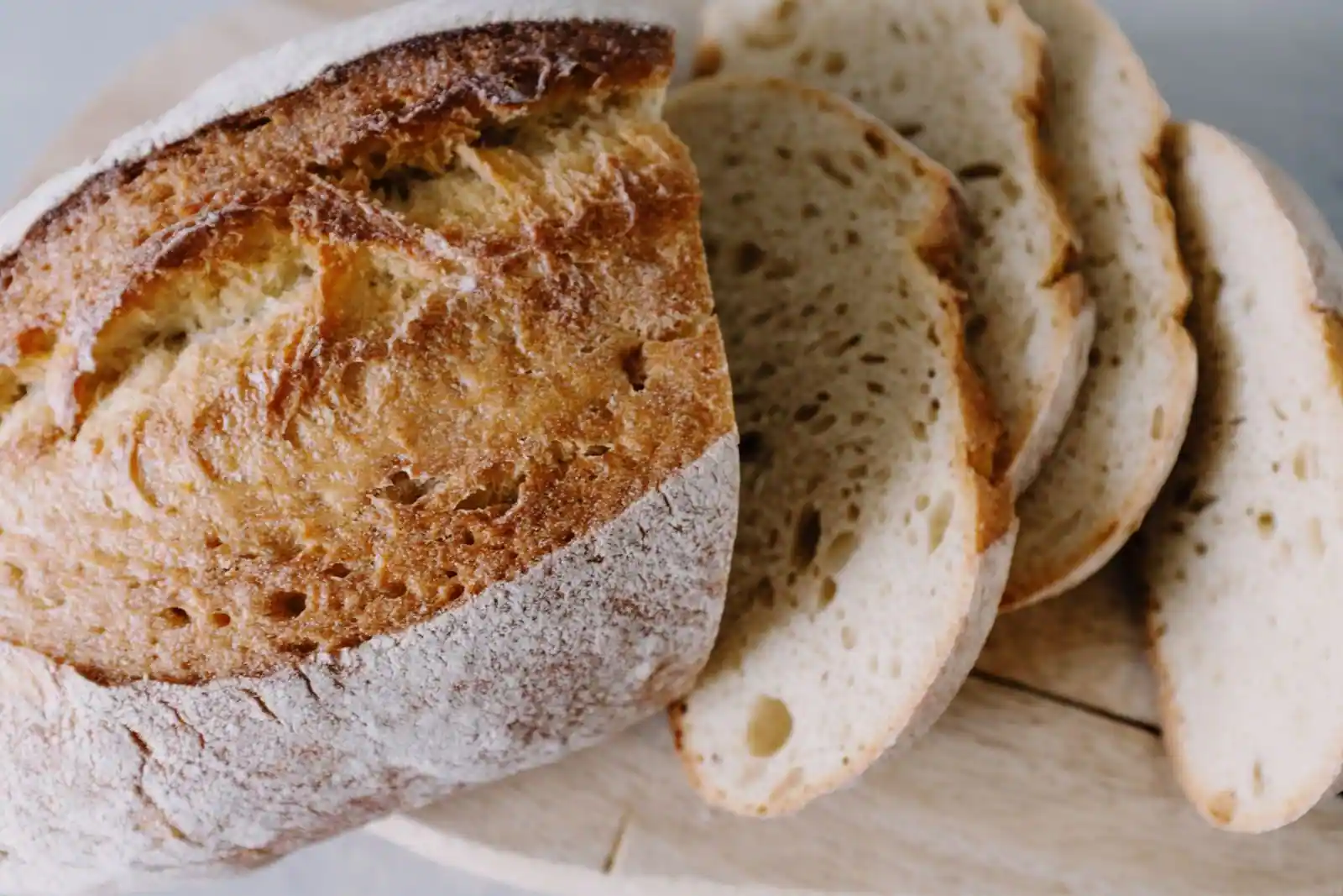 Pain maison rustique partiellement tranché, croûte farinée, posé sur une planche en bois