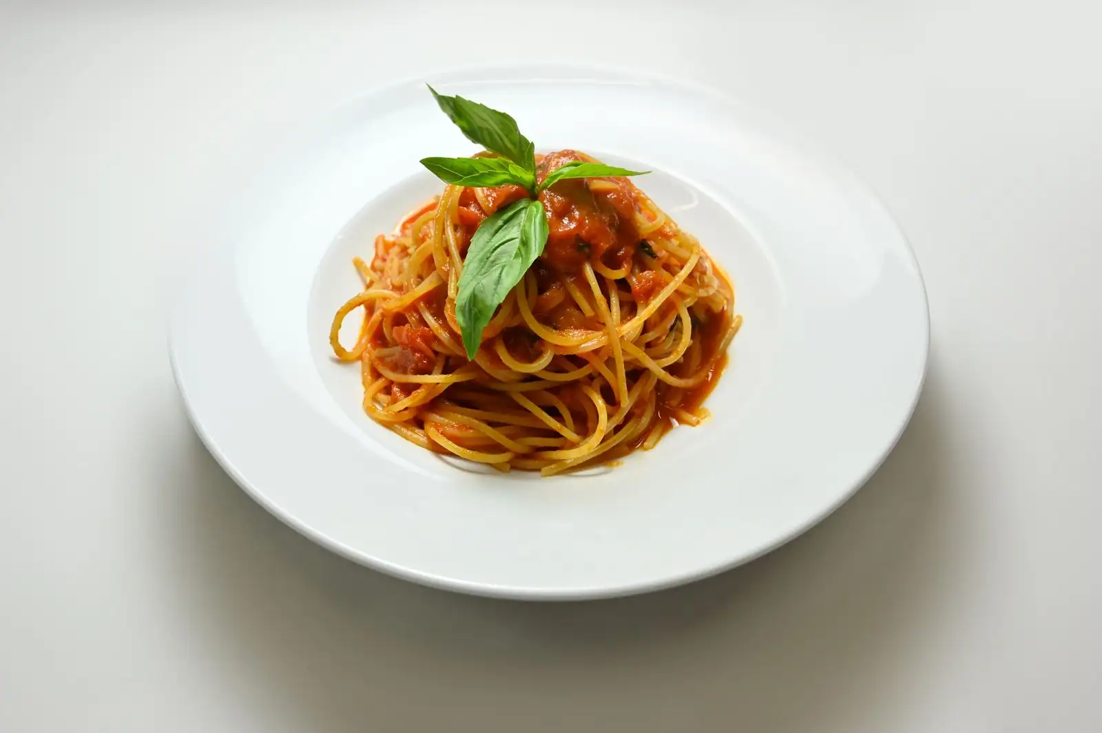 Assiette de spaghetti à la sauce tomate garnie d'une feuille de basilic frais