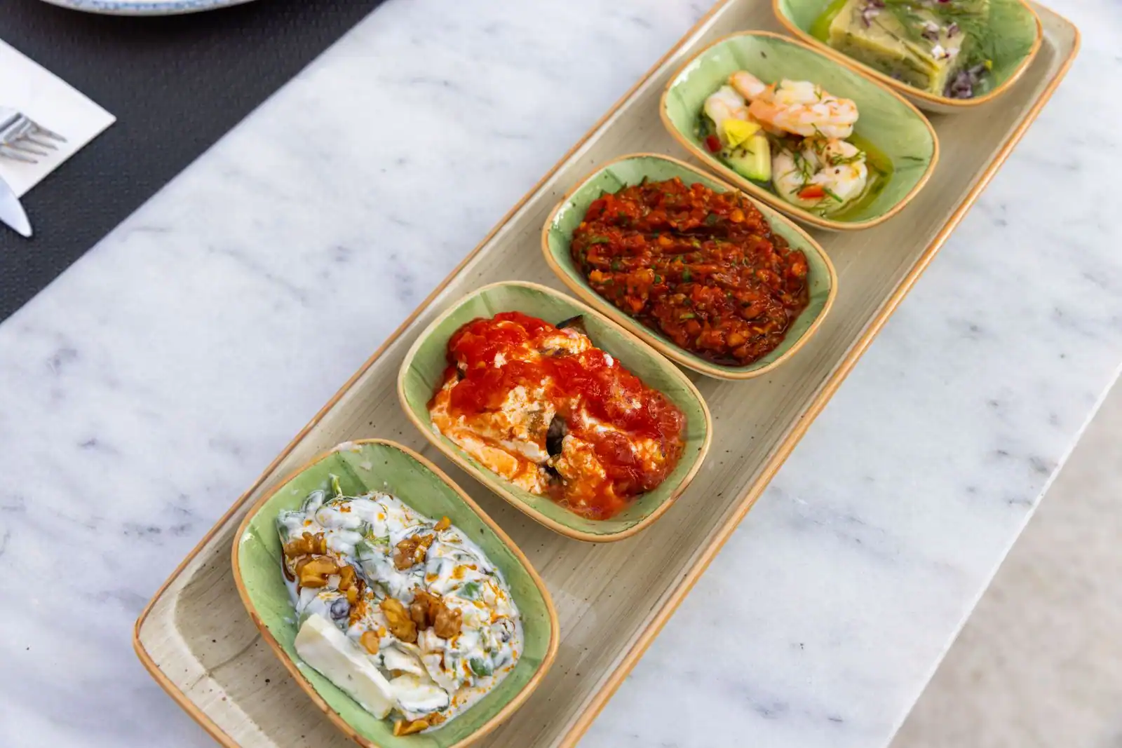 Plateau de mezze méditerranéens à partager, petites assiettes de dips et de spécialités sur du marbre