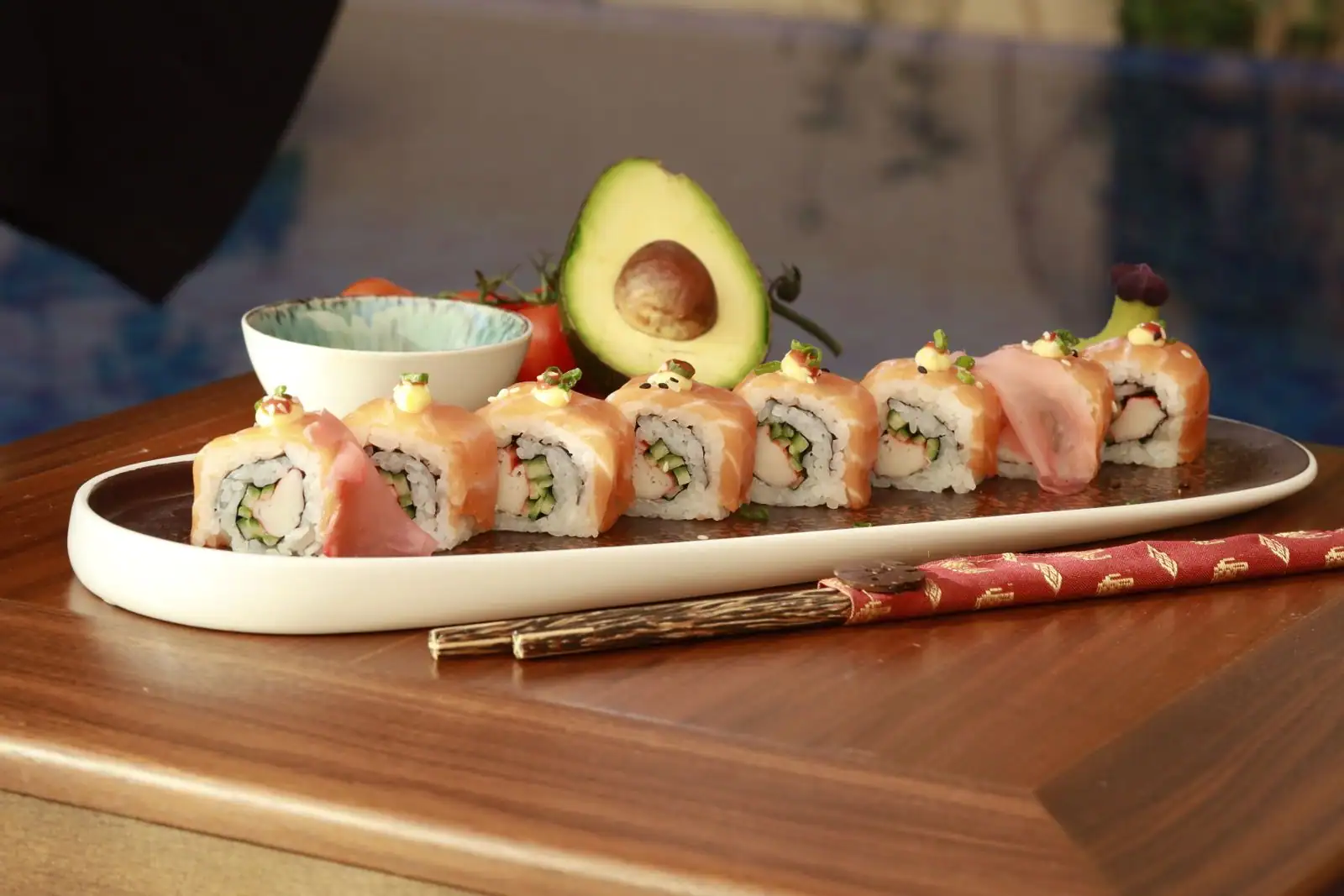 Plateau de sushis maison nappés de saumon, avec gingembre, avocat et baguettes