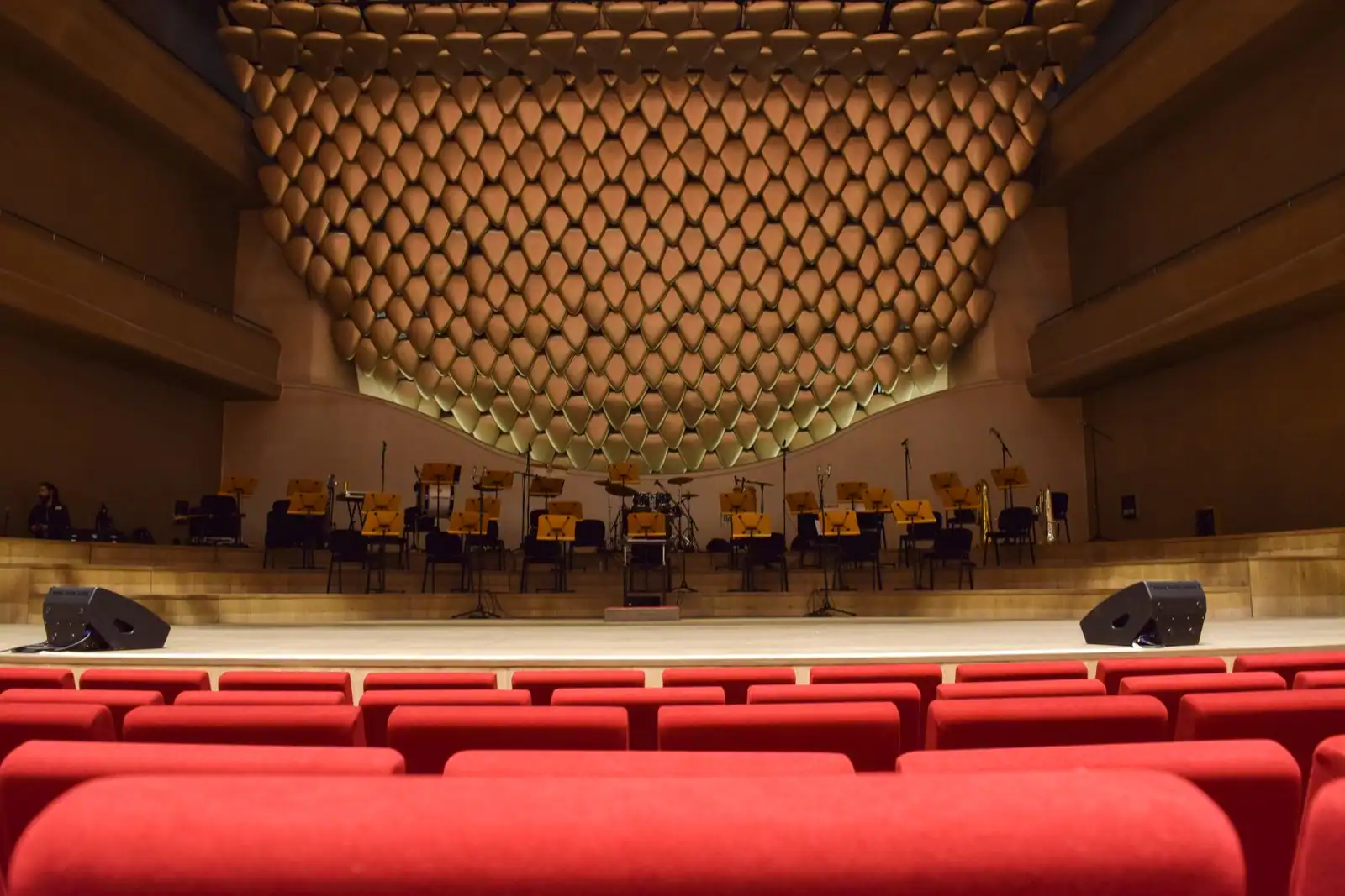 Salle de concert moderne aux fauteuils rouges, scène dressée pour un orchestre face au public