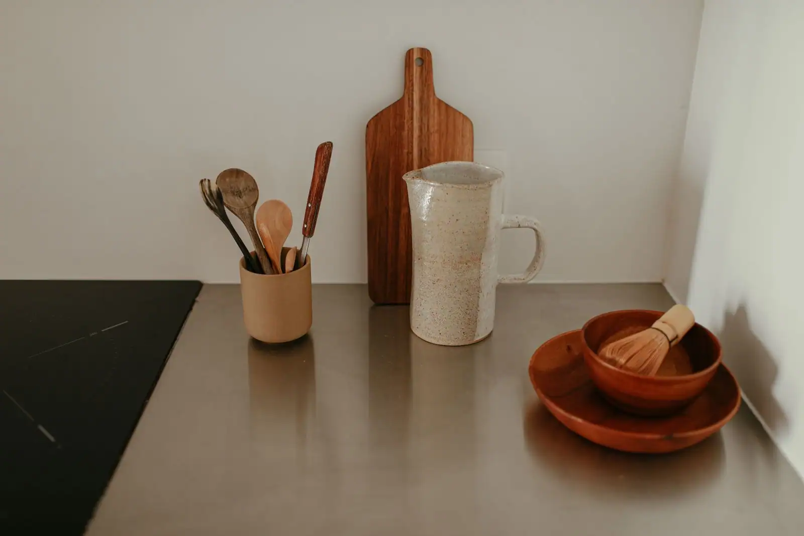 Ustensiles de cuisine en bois et en inox posés sur un plan de travail