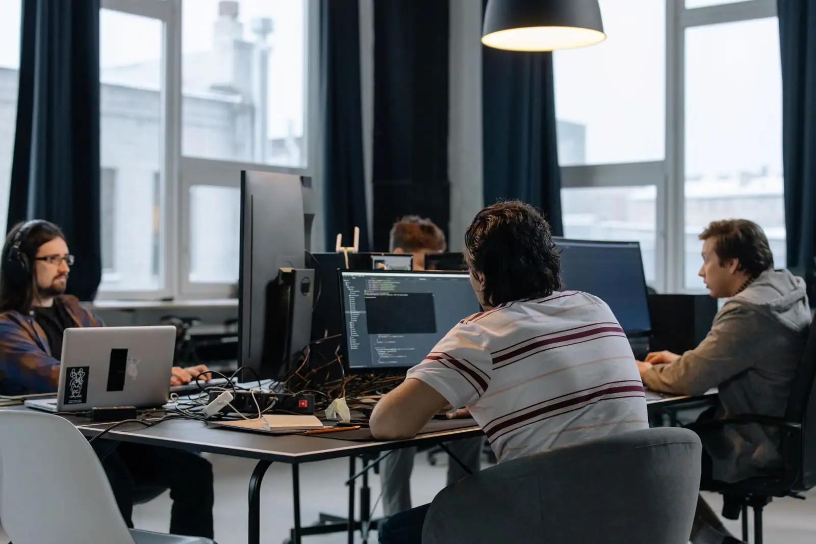 Développeurs au travail dans un bureau en open space, avec du code affiché sur un écran