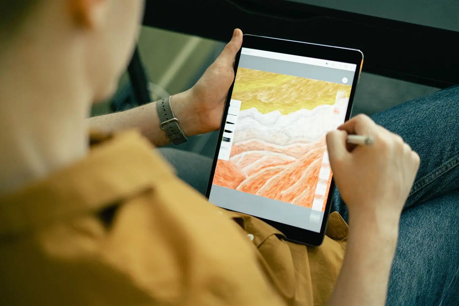 Personne dessinant au stylet sur une tablette tenue à la main, application de dessin ouverte à l'écran
