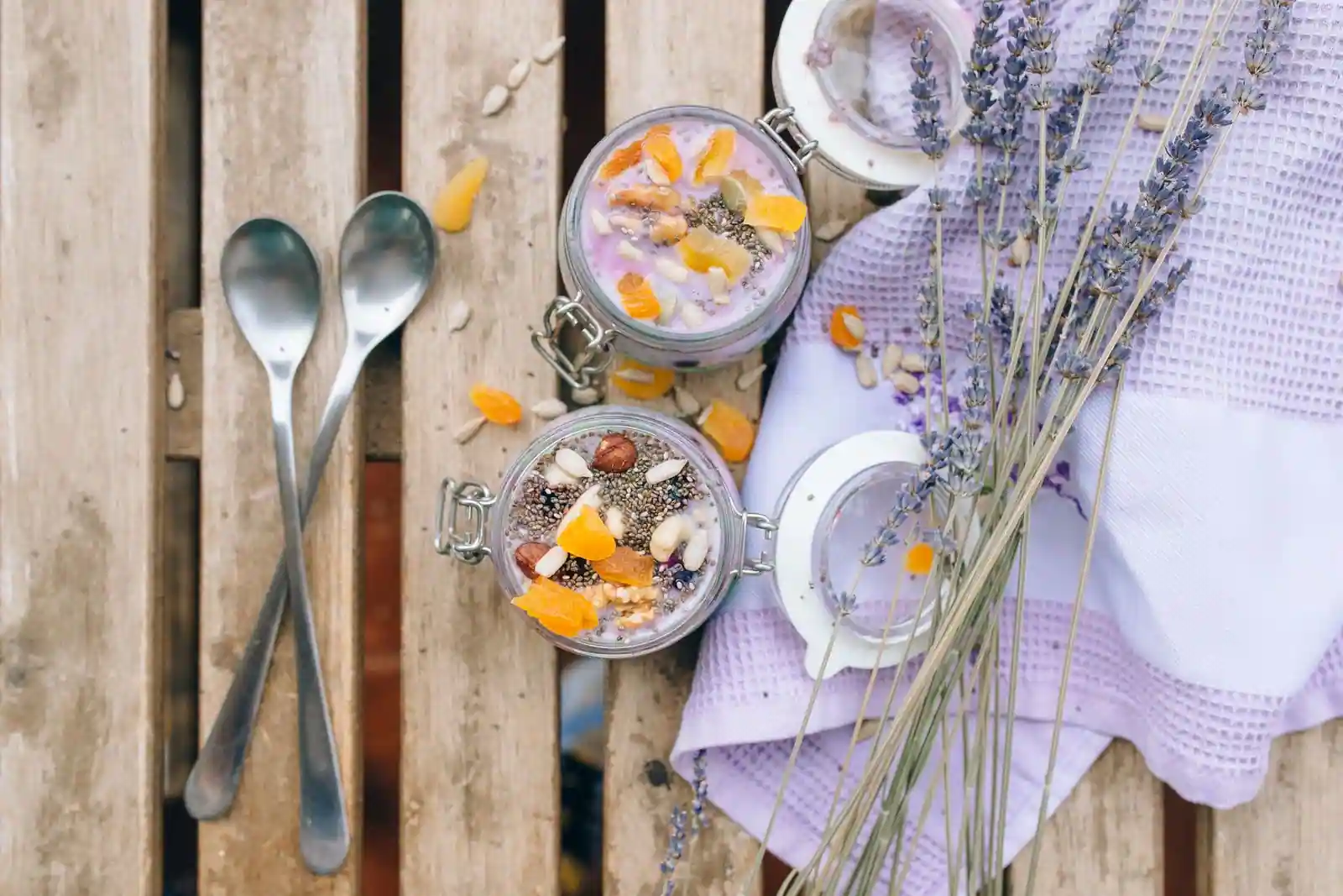 Pudding de graines de chia servi en bocaux, garni d’abricots secs, de noisettes et de graines.