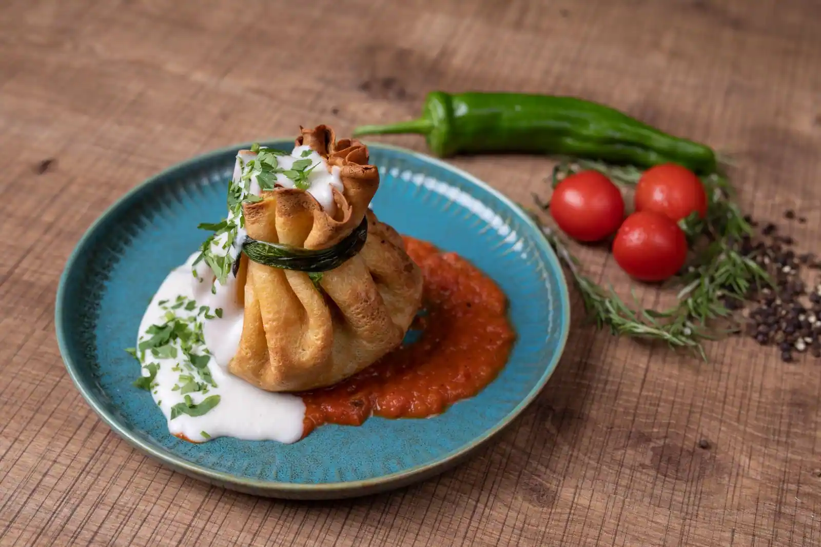 Entrée chaude en pâte feuilletée dressée à l'assiette avec un coulis de tomate et une crème.