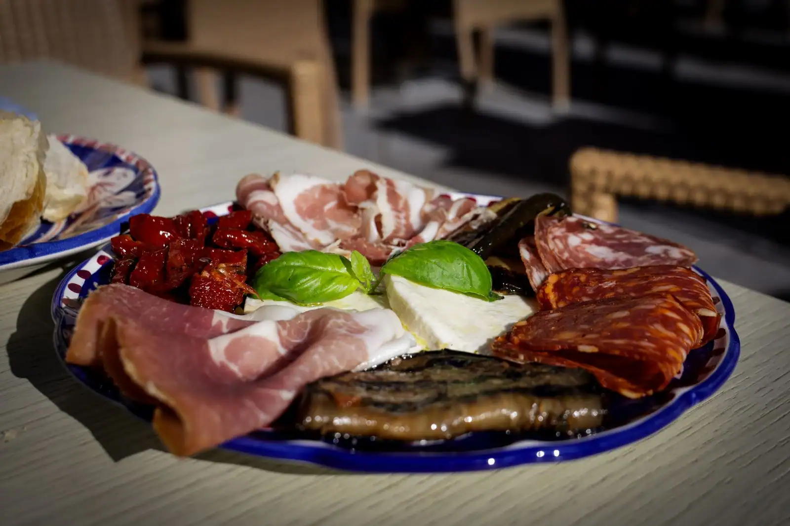 Assiette d'antipasti : charcuteries tranchées, salami, mozzarella au basilic, tomates séchées et aubergines grillées.