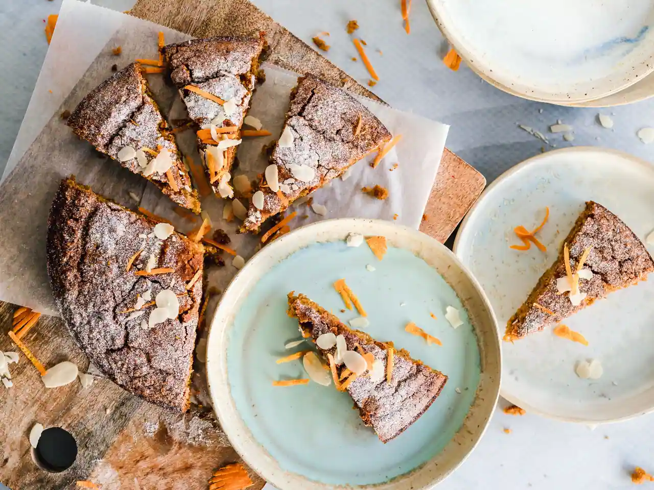 Gâteau maison aux carottes et aux amandes effilées, coupé en parts, mie dense et voile de sucre glace