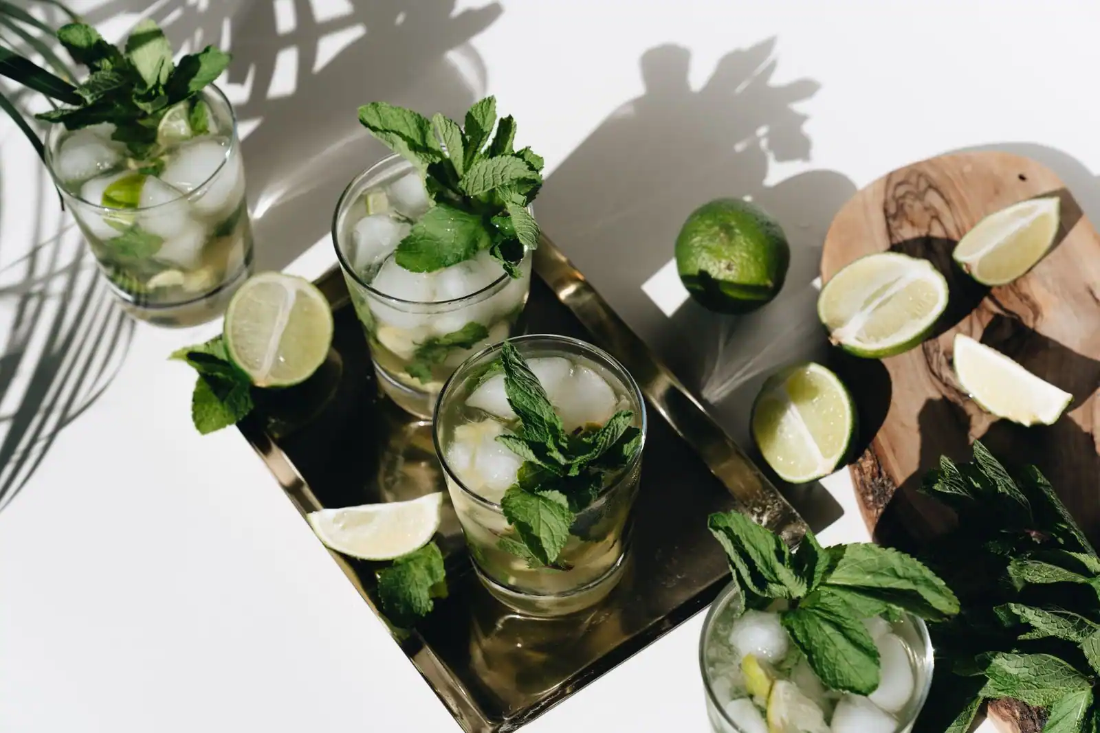 Verres de mojito sans alcool à la menthe fraîche et au citron vert sur glace, sur un plateau.