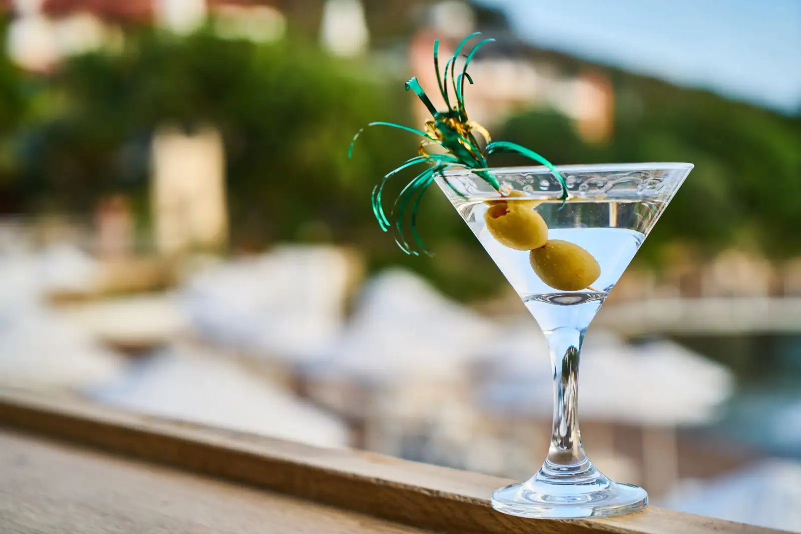 Verre à Martini rempli d'un cocktail limpide, garni d'une olive, posé sur un comptoir de bar.
