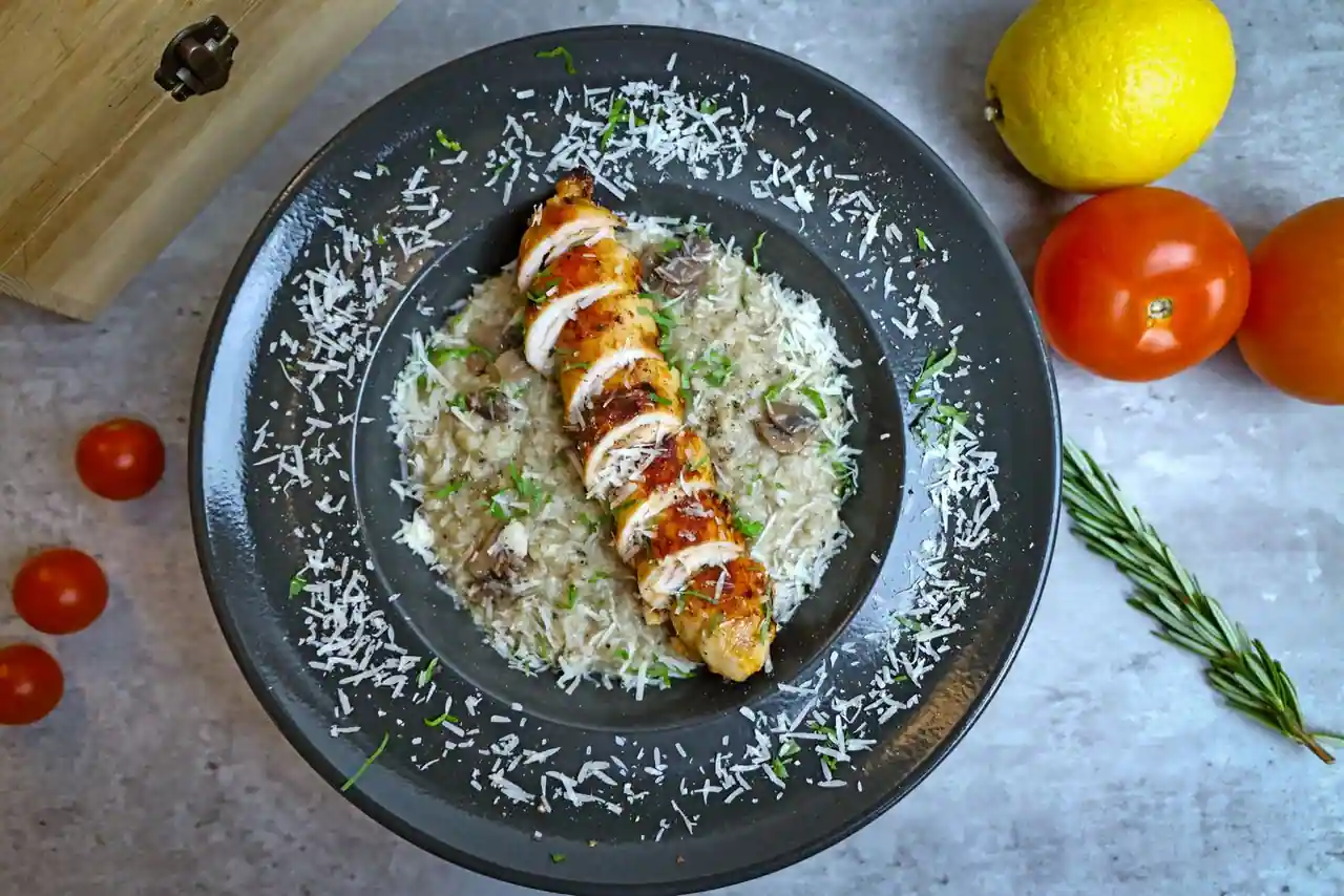 Risotto crémeux au parmesan avec tranches de poulet et morceaux de champignons
